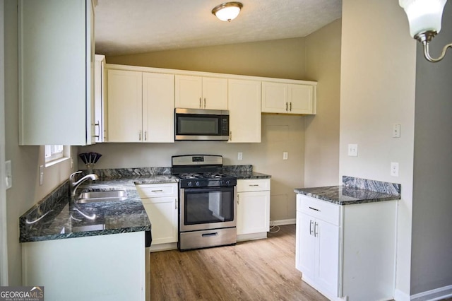 kitchen featuring white cabinetry, sink, vaulted ceiling, and appliances with stainless steel finishes