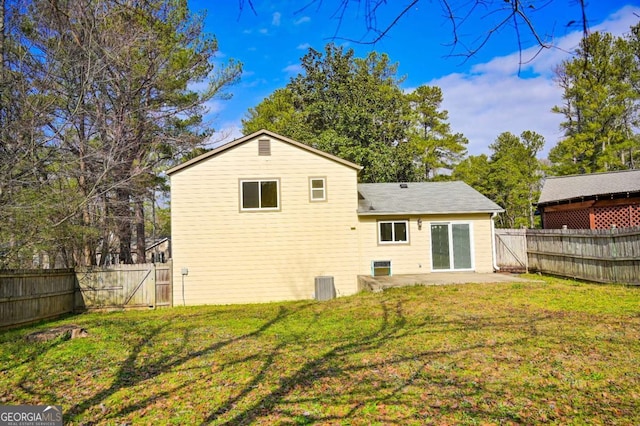 rear view of property featuring a yard, central AC unit, and a patio