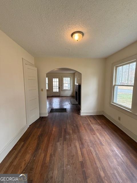 unfurnished living room featuring a textured ceiling and dark hardwood / wood-style flooring