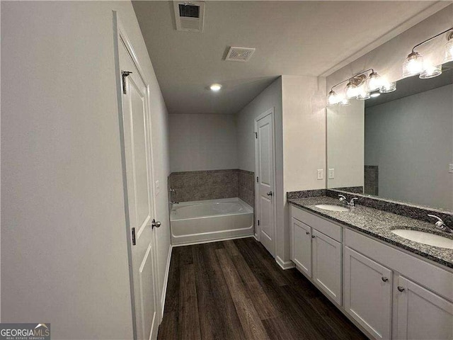 bathroom with wood-type flooring, a bathing tub, and vanity