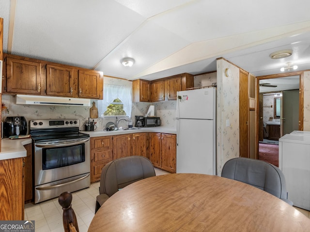 kitchen featuring sink, stainless steel range with electric cooktop, vaulted ceiling, white refrigerator, and washer / clothes dryer