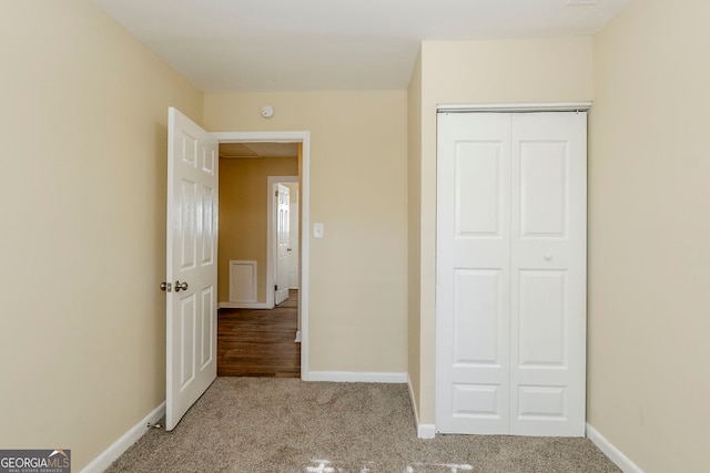 unfurnished bedroom with light carpet and a closet