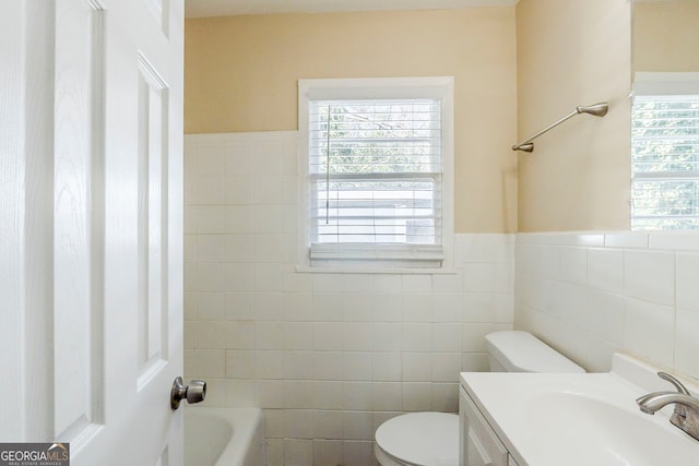 bathroom featuring a bathing tub, a healthy amount of sunlight, vanity, and toilet