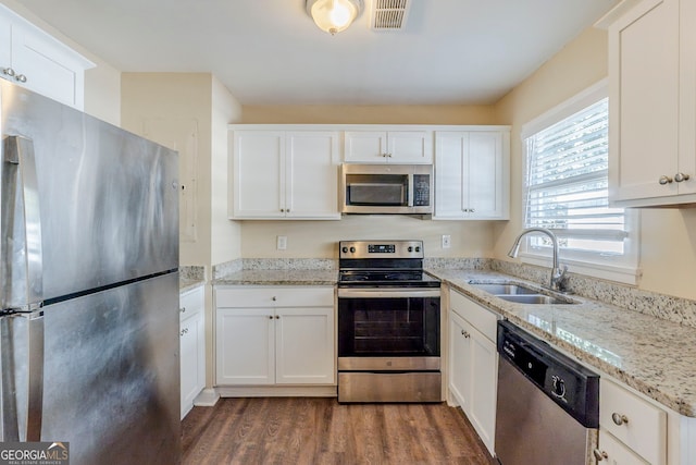 kitchen with appliances with stainless steel finishes, light stone countertops, sink, and white cabinets