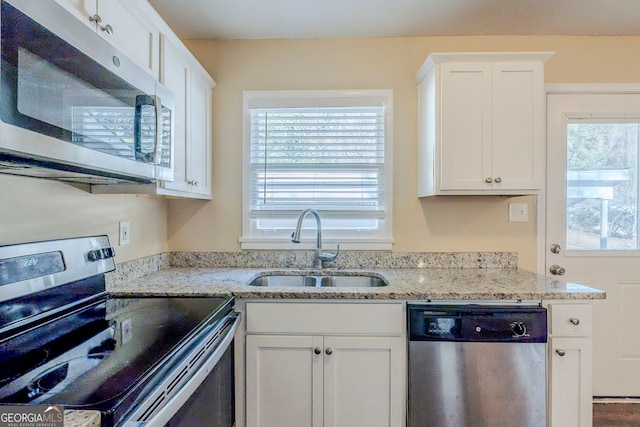 kitchen with appliances with stainless steel finishes, light stone countertops, sink, and white cabinets