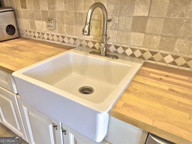 room details with white cabinetry, butcher block counters, sink, and decorative backsplash