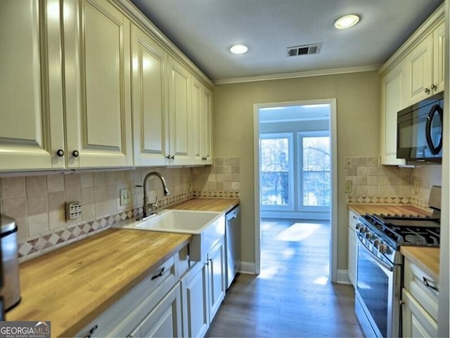 kitchen with crown molding, appliances with stainless steel finishes, wooden counters, and sink