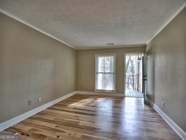 empty room with ornamental molding, a textured ceiling, and light hardwood / wood-style floors