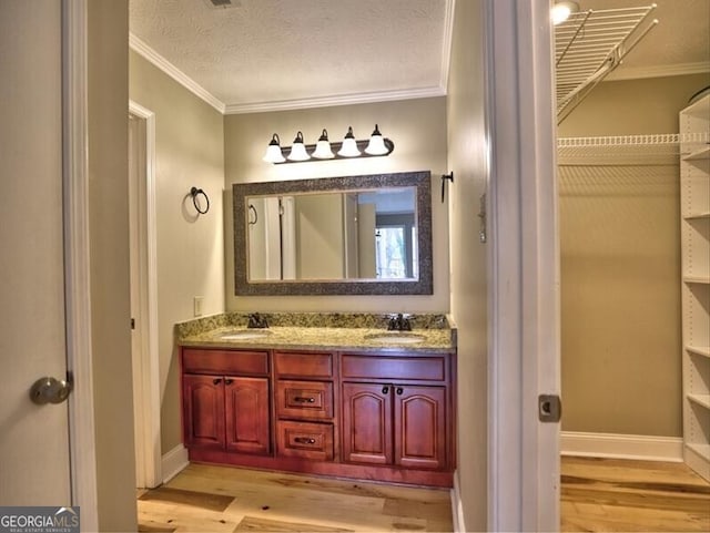 bathroom featuring crown molding, vanity, hardwood / wood-style floors, and a textured ceiling