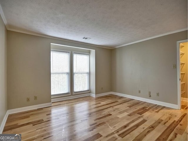 empty room with crown molding, a textured ceiling, and light hardwood / wood-style flooring