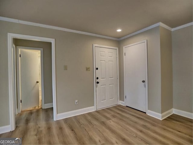 entryway with ornamental molding and light hardwood / wood-style flooring