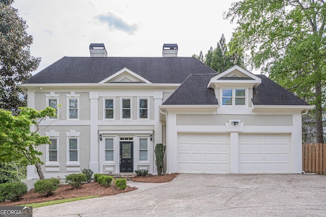 view of front of home featuring a chimney, concrete driveway, stucco siding, and fence