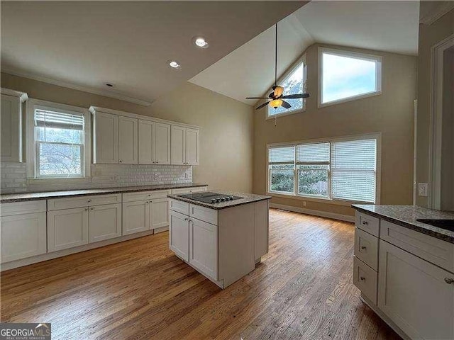 kitchen featuring a center island, white cabinets, light hardwood / wood-style floors, and dark stone counters