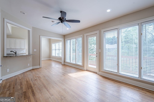 unfurnished living room with light wood-type flooring, baseboards, recessed lighting, ceiling fan, and a sink