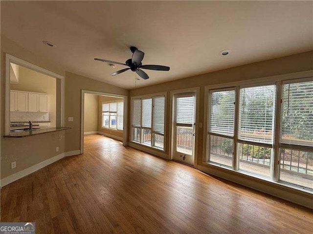 interior space with sink, a wealth of natural light, light hardwood / wood-style floors, and vaulted ceiling