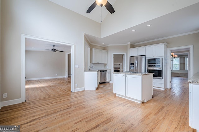 kitchen with white cabinets, a sink, ceiling fan, stainless steel appliances, and a kitchen island