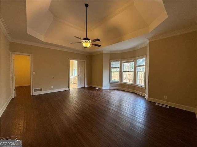 unfurnished room featuring ornamental molding, dark hardwood / wood-style floors, ceiling fan, and a tray ceiling