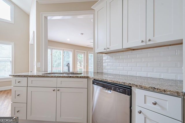 kitchen with white cabinetry, light stone counters, dishwasher, a sink, and backsplash