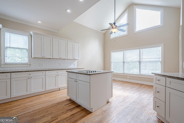 kitchen featuring white cabinetry, light stone countertops, decorative backsplash, light wood finished floors, and ceiling fan