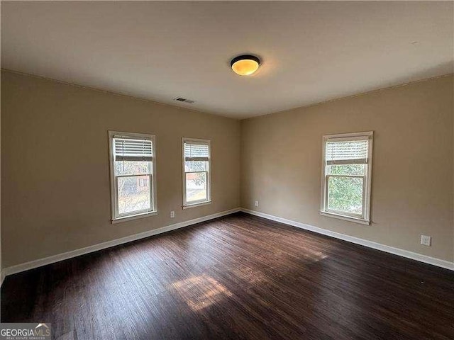 unfurnished room with dark hardwood / wood-style floors and a wealth of natural light