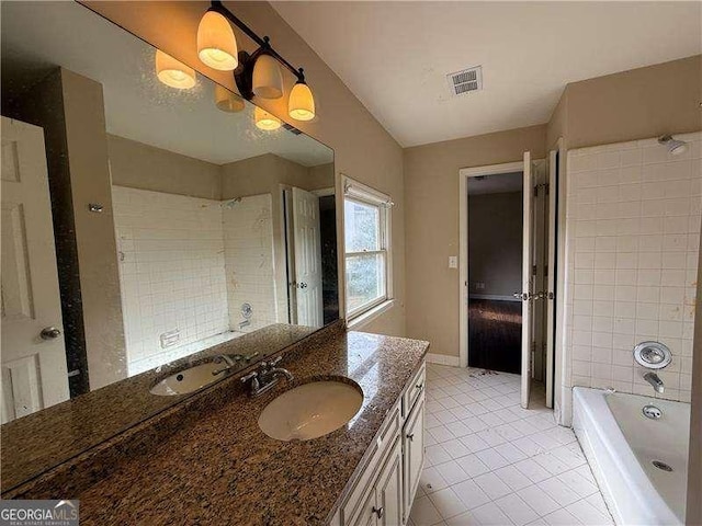 bathroom featuring tile patterned flooring, vanity, and tiled shower / bath