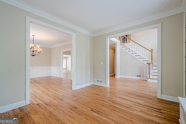 empty room with ornamental molding, visible vents, an inviting chandelier, and stairs