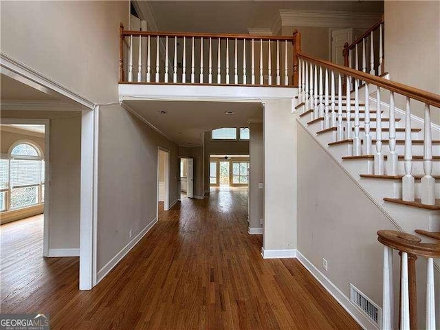 interior space with dark hardwood / wood-style flooring, crown molding, and a high ceiling