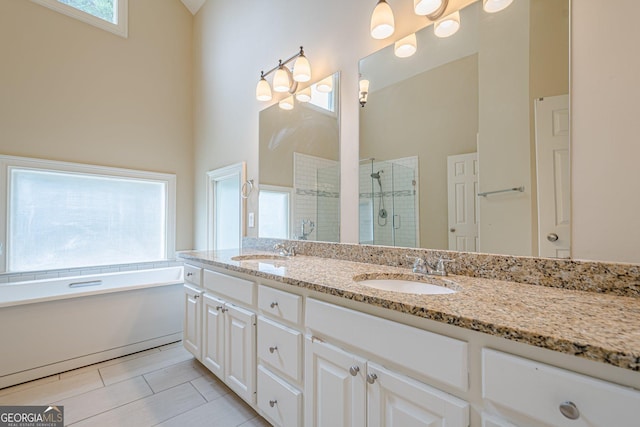 bathroom featuring a shower stall, a garden tub, double vanity, and a sink
