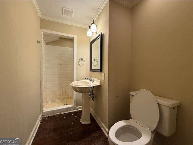 bathroom featuring wood-type flooring, ornamental molding, toilet, and tiled shower