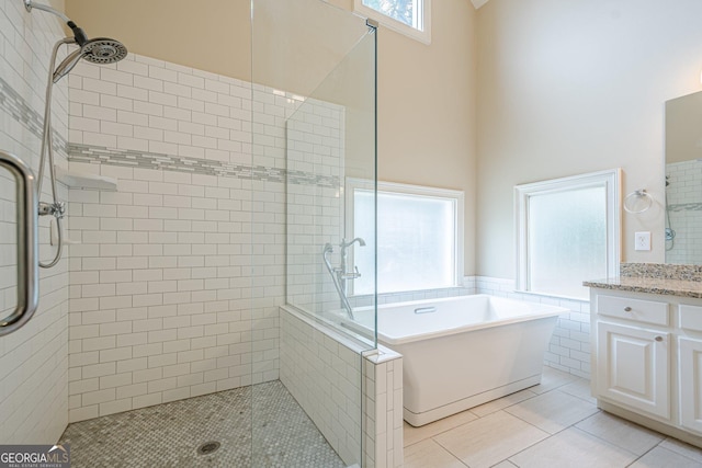 full bathroom with tile patterned flooring, vanity, a stall shower, and a soaking tub