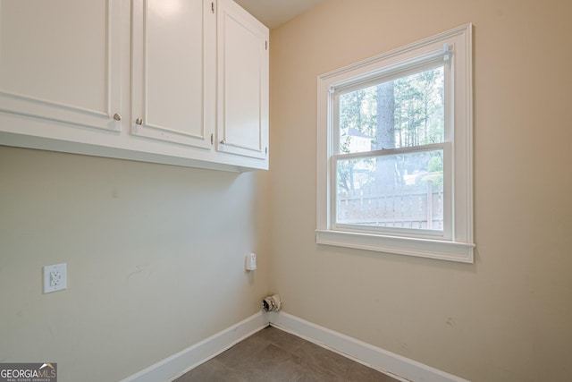 clothes washing area featuring baseboards and cabinet space