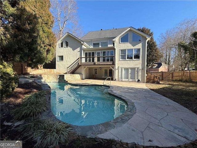 back of property with a fenced in pool and a patio area