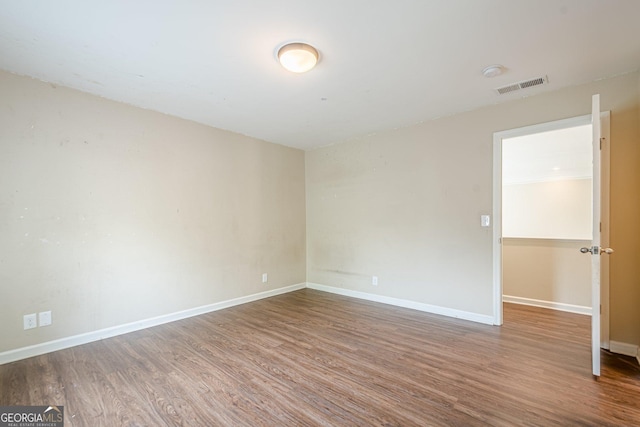 unfurnished room featuring wood finished floors, baseboards, and visible vents