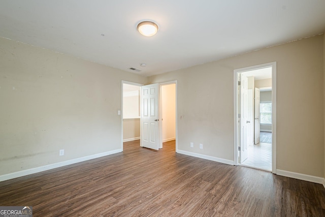 unfurnished bedroom with wood finished floors, baseboards, and visible vents