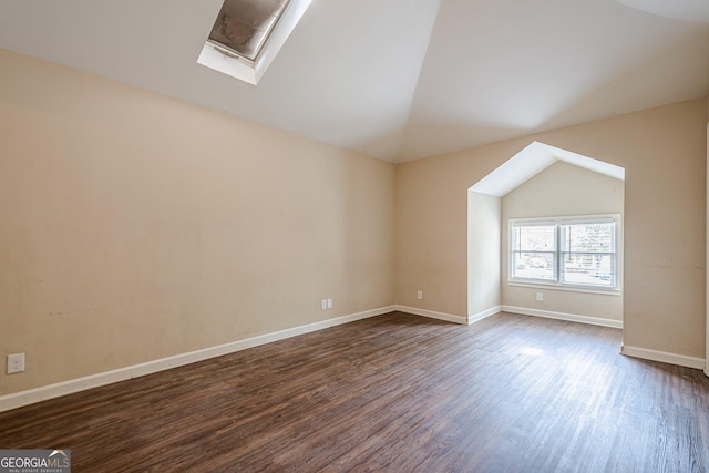 additional living space featuring baseboards, lofted ceiling with skylight, and dark wood-style floors
