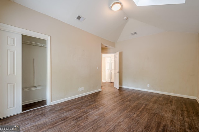 unfurnished bedroom featuring vaulted ceiling with skylight, visible vents, baseboards, and wood finished floors