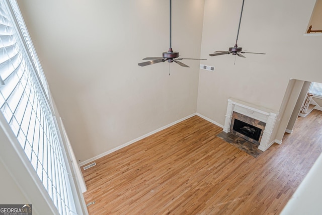 unfurnished living room with light wood-type flooring, baseboards, a ceiling fan, and visible vents