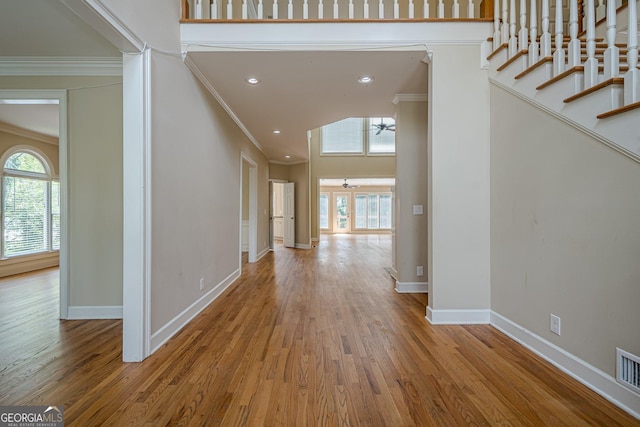 entryway with ornamental molding, a wealth of natural light, and wood finished floors