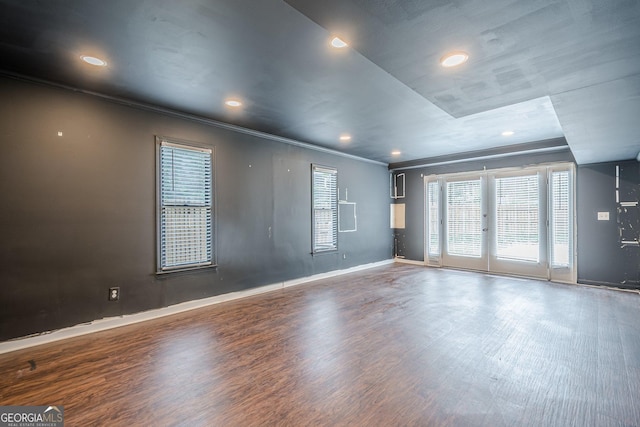 spare room with crown molding, wood finished floors, baseboards, and recessed lighting