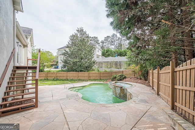 view of swimming pool featuring a pool with connected hot tub, a fenced backyard, stairway, and a patio