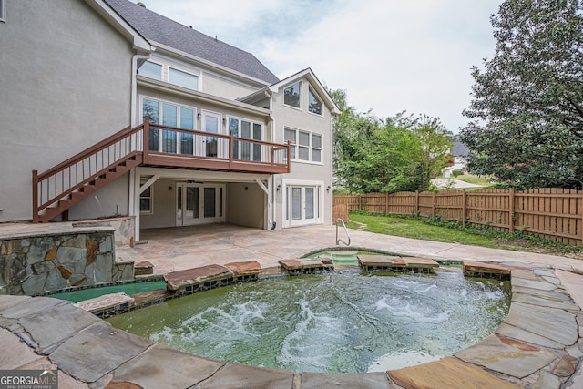 rear view of house with stucco siding, stairway, french doors, a small pond, and fence