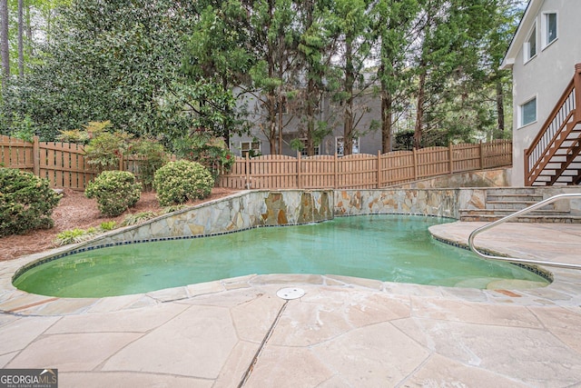 view of swimming pool featuring a patio area, stairway, and a fenced backyard