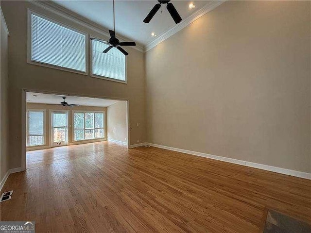 unfurnished living room with crown molding, ceiling fan, wood-type flooring, and high vaulted ceiling