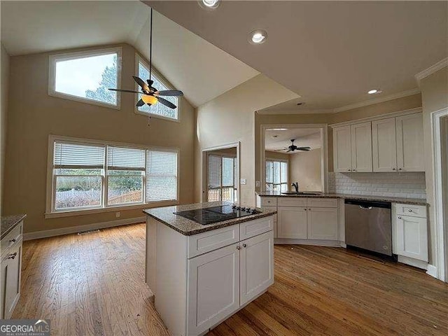 kitchen with black electric stovetop, stainless steel dishwasher, white cabinets, and light hardwood / wood-style flooring