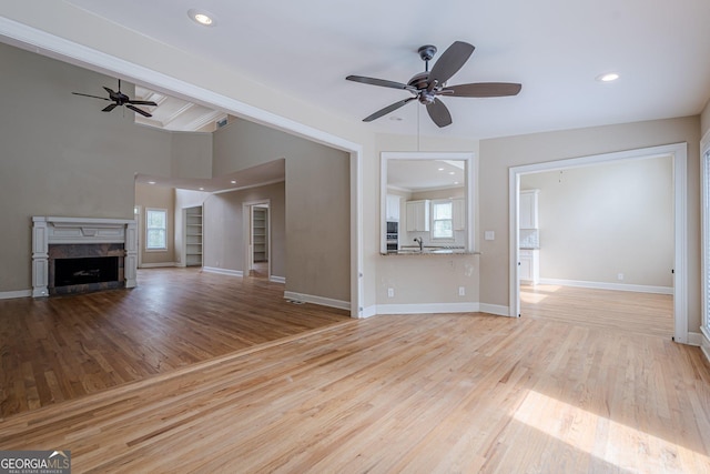 unfurnished living room with a sink, a ceiling fan, a fireplace, recessed lighting, and wood finished floors