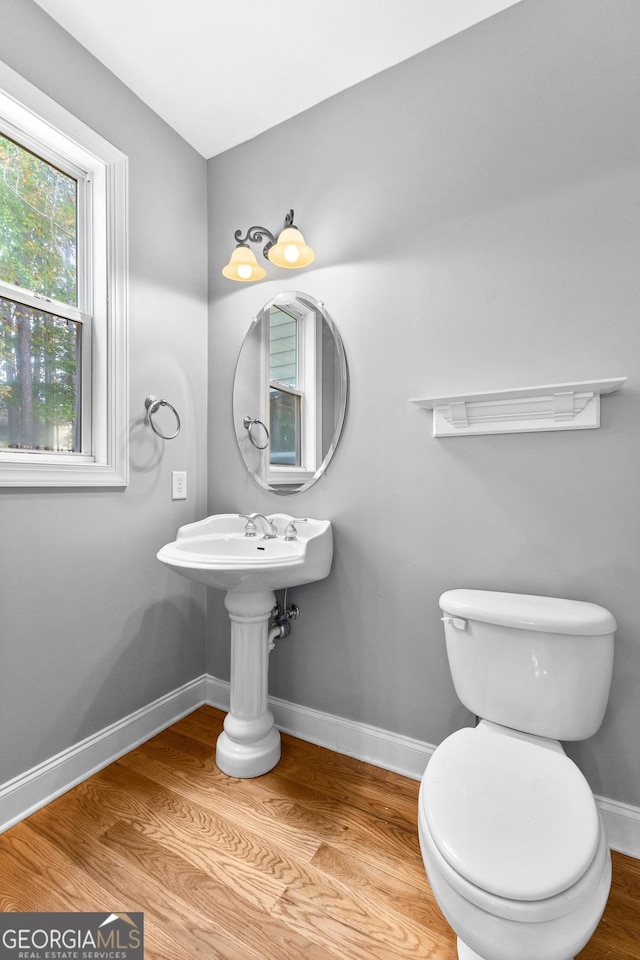 bathroom with toilet, baseboards, and wood finished floors