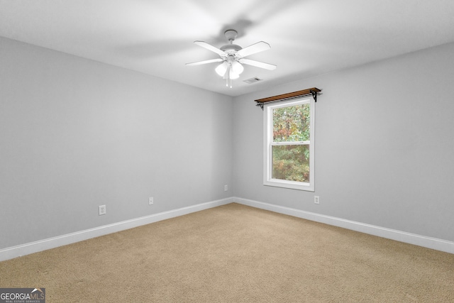 spare room featuring carpet flooring, ceiling fan, visible vents, and baseboards