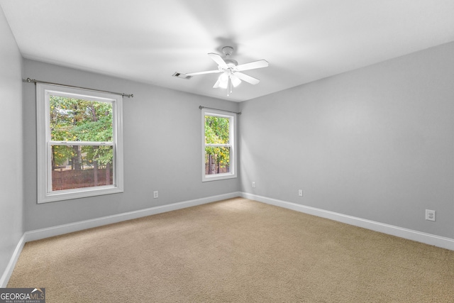 empty room featuring carpet floors, baseboards, visible vents, and a ceiling fan