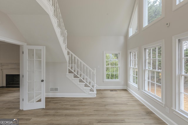 unfurnished living room with a wealth of natural light, high vaulted ceiling, and light hardwood / wood-style flooring