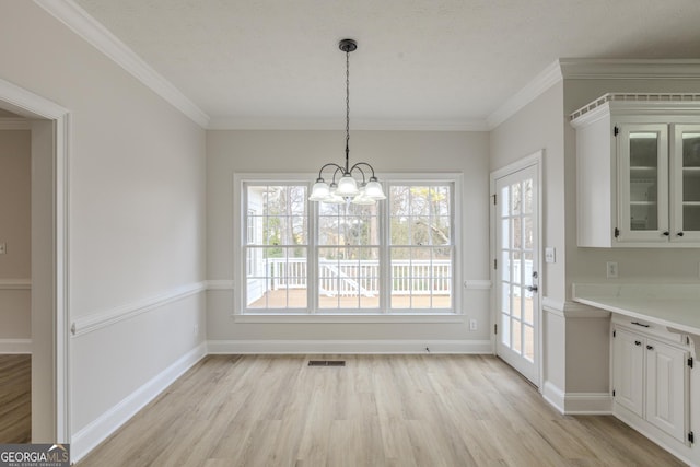 unfurnished dining area featuring crown molding, a healthy amount of sunlight, and light hardwood / wood-style floors